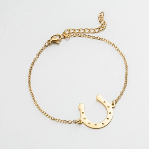 Macro detail of golden U-shaped horseshoe pendant bracelet with adjustable lobster clasp