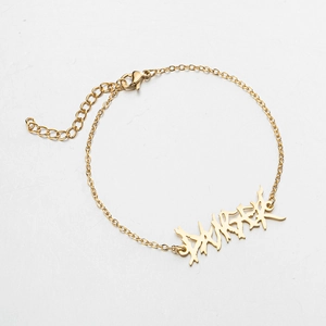 Detail of gold gothic graffiti pendant on minimalist adjustable stainless steel chain