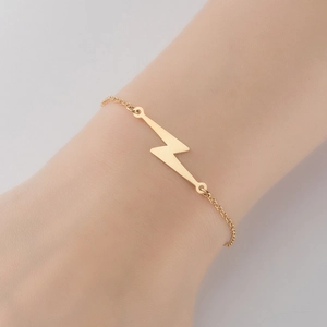 Close-up of minimalist gold-plated stainless steel lightning bolt pendant bracelet on wrist
