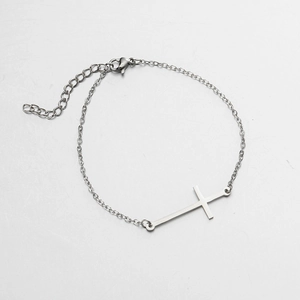 Détail d'un bracelet à pendentif croix argentée avec fermoir mousqueton et extension