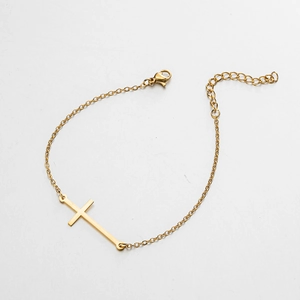 Détail d'un bracelet croix dorée avec fermoir homard ajustable et chaîne fine en O