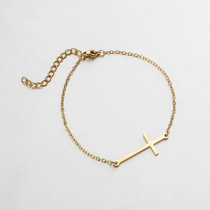 Détail macro du pendentif croix dorée sur un bracelet à chaîne maille ajustable