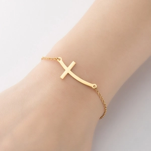 Dettaglio di un bracciale in acciaio inossidabile dorato con ciondolo a croce