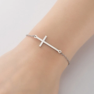 Gros plan d'un bracelet minimaliste en argent avec croix sur le poignet d'une femme fine
