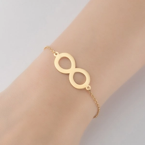 Gros plan détaillé du bracelet symbole infini doré au poignet avec fine chaîne minimaliste