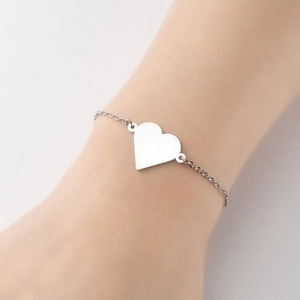 Detailed close-up of a minimalist silver heart charm on a delicate cable chain bracelet