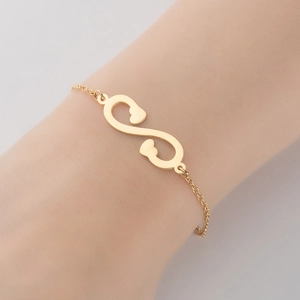 Détail du bracelet cœur et infini en acier inoxydable doré sur le poignet d'une femme