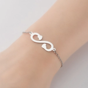 Gros plan d'un bracelet cœur et infini en argent porté au poignet d'une femme