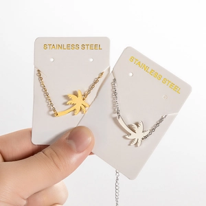 Gold and silver stainless steel coconut tree charm bracelets shown on packaging cards