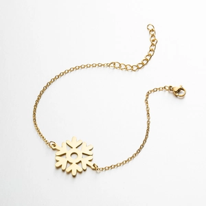 Detailed macro view of a gold snowflake pendant bracelet with lobster clasp and chain