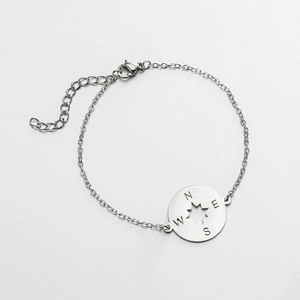 Macro detail of stainless steel compass pendant bracelet with N E S W engraving