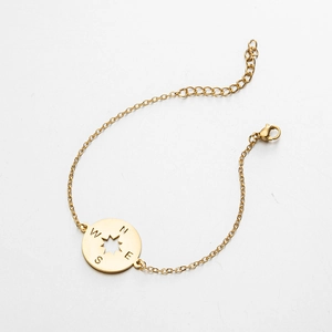 Detail view of gold compass pendant with North East South West engraving and octagonal star