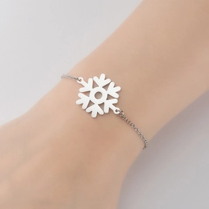 Detail of silver snowflake charm bracelet on wrist showing winter minimalist fashion