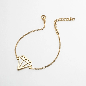 Detailed macro view of gold chain bracelet featuring a geometric hollow diamond pendant