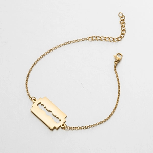 Detailed macro view of a gold razor blade pendant on a punk style stainless steel chain