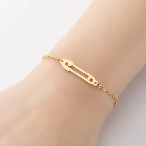 Bracelet minimaliste doré avec pendentif épingle à nourrice sur poignet féminin chic