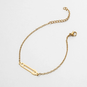 Détail du bracelet doré avec breloque trombone, fermoir mousqueton et chaîne d'extension