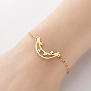 Minimalist gold moon and stars pendant bracelet on female wrist with elegant thin chain