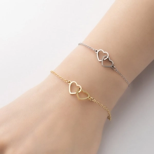 Dettaglio dei pendenti a cuori intrecciati su bracciali in acciaio dorato e argento