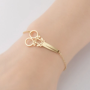 Vintage gold scissor cuff bracelet with intricate scrollwork on a minimalist chain