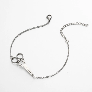 Detailed macro of vintage silver scissor pendant with intricate hollow pattern and clasp
