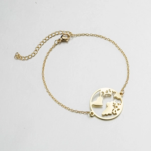 Detail of gold chain bracelet with a hollow circular world map pendant and lobster clasp