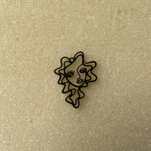 Detail of abstract hollow face pendant in black matte finish for DIY jewelry designs