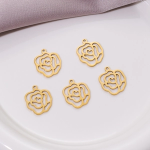 Macro view of five golden rose flower pendants with heart centers on a white ceramic plate
