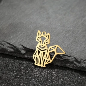 Macro view of geometric fox charms in golden finish on dark textured stone base