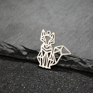 Macro shot of silver origami fox pendant with hollow metal design on stone texture