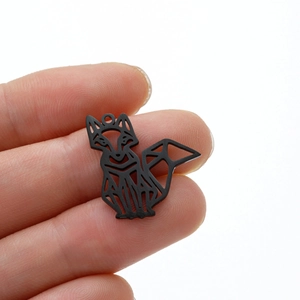 Detail of geometric origami fox pendant in black matte stainless steel held by fingers