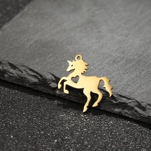 Detailed view of a golden unicorn pendant with a heart-shaped cutout on dark stone surface