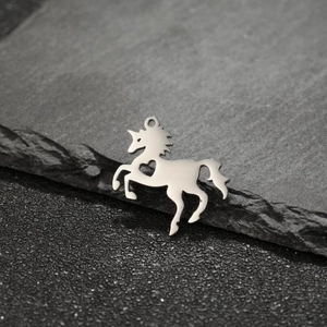 Macro detail of silver unicorn pendant with heart cutout on dark textured stone