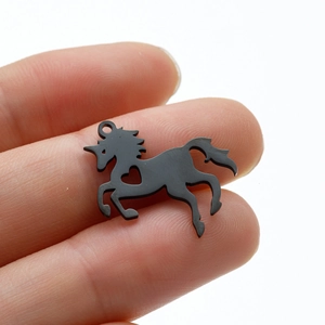 Minimalist black stainless steel unicorn pendant with heart cutout held by hand