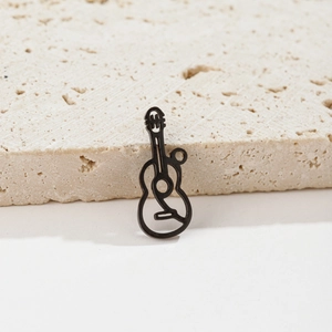 Detailed view of a minimalist black stainless steel guitar pendant on beige stone