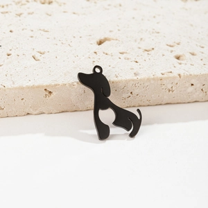 Macro view of a black stainless steel hollow dog pendant resting on a natural stone surface