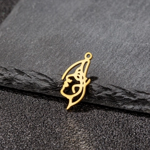 Macro shot of 18K gold-plated abstract face pendant on dark slate stone background