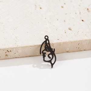 Detailed view of matte black abstract face pendant on stone with soft shadows