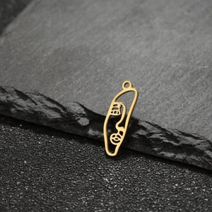 Macro shot of abstract gold wireface pendant leaning on textured dark grey stone edge
