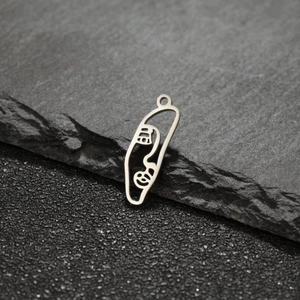 Detailed view of silver stainless steel abstract face pendant on dark natural stone
