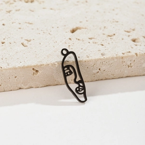 Macro detail of abstract face metal pendant with matte black finish on stone background