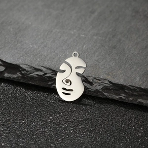 Artistic abstract hollow face metal pendant resting on a dark natural textured rock