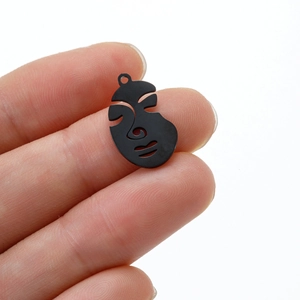 Macro shot of abstract half-face metal pendant with black matte finish and hollow detail