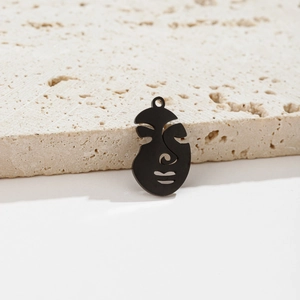 Detailed view of matte black abstract face pendants on minimalist travertine stone