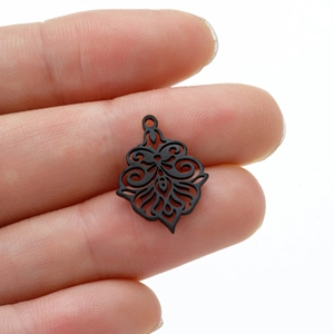 Macro shot of a black laser-cut floral stainless steel pendant held in hand for scale