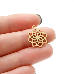 Macro view of a gold-toned stainless steel mandala flower pendant with hollow-out design