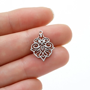 Detailed close-up of a silver hollow flower pendant with vintage scrollwork patterns