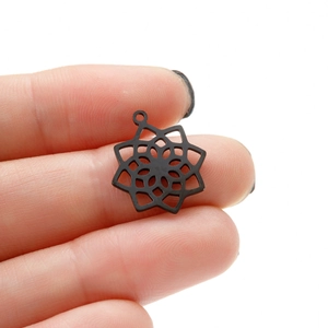 Close-up of black mandala flower pendant held between fingers to show detailed cutout size