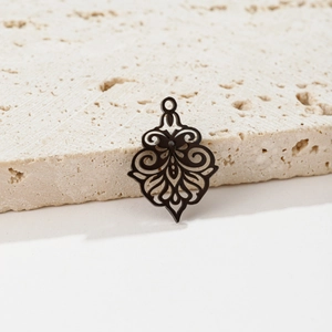 Close-up of vintage hollow bronze flower pendant on textured travertine stone