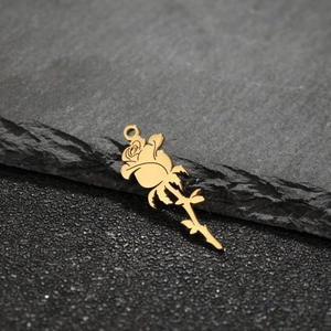 Close-up of 18k gold plated rose pendant with detailed leaves on dark stone background